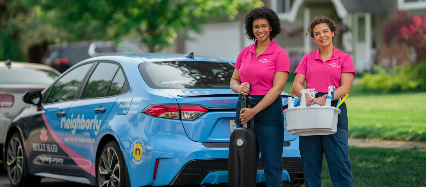 Molly Maid professionals standing beside a branded car.